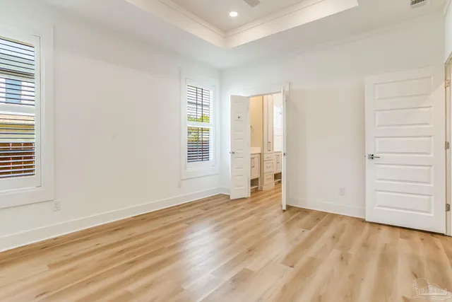 a view of a hallway with wooden floor and a bathroom