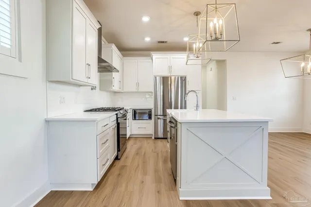 an empty room with wooden floor cabinet and windows