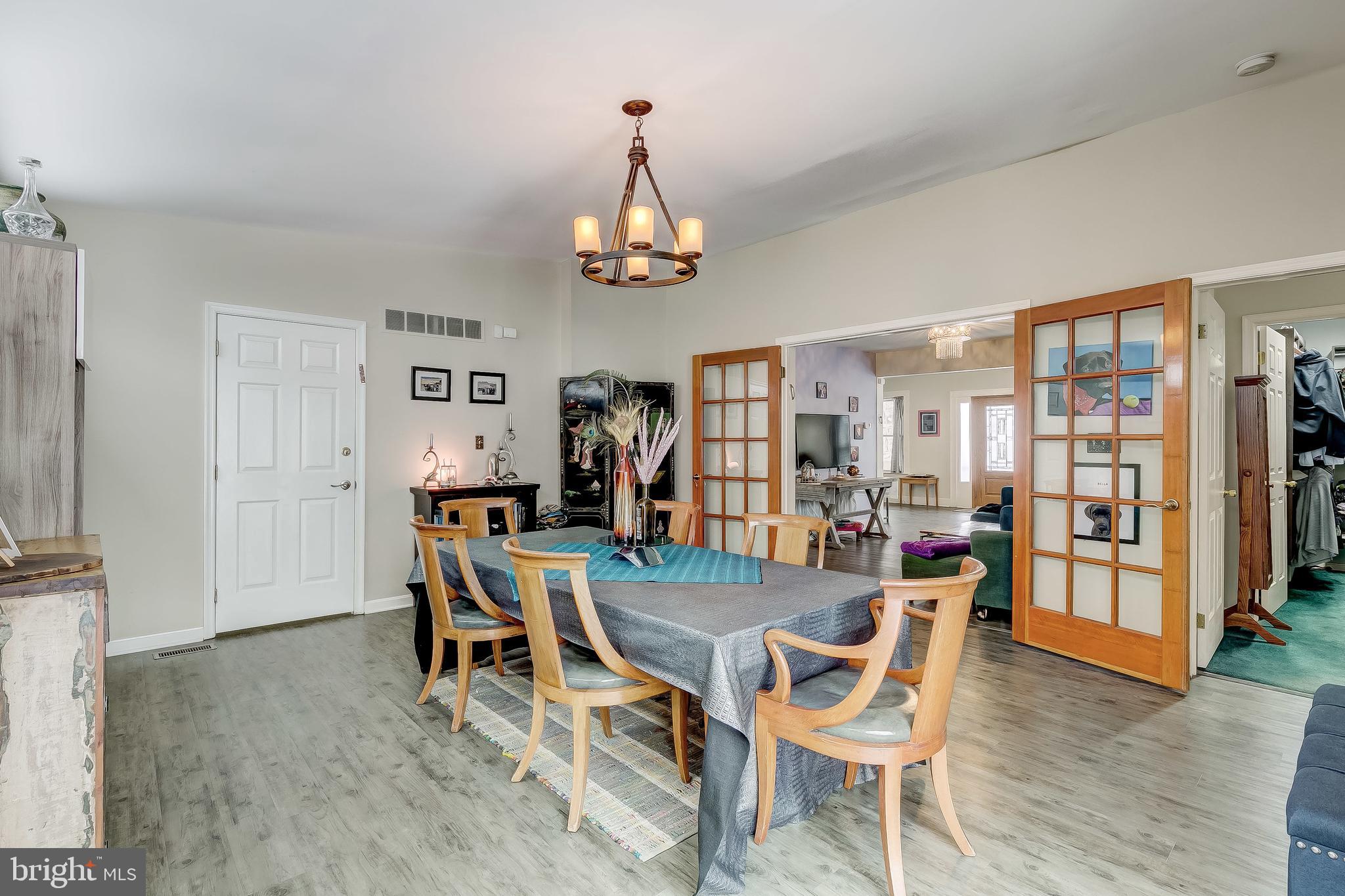 2416 Steele Road Baltimore, MD 21209 - Photo 2 of 47 a dining room with wooden floor a chandelier a glass table and chairs