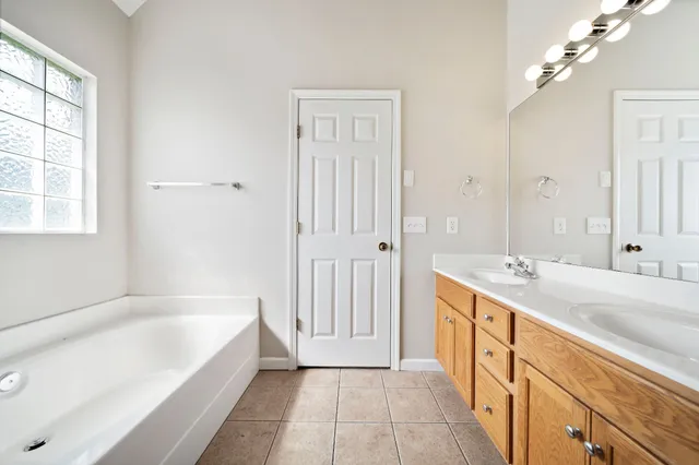 a spacious bathroom with a tub sink and mirror