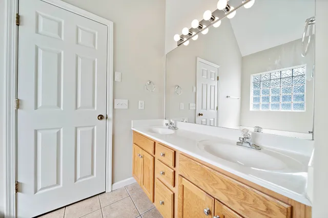 a bathroom with a double vanity sink a large mirror and a bathtub