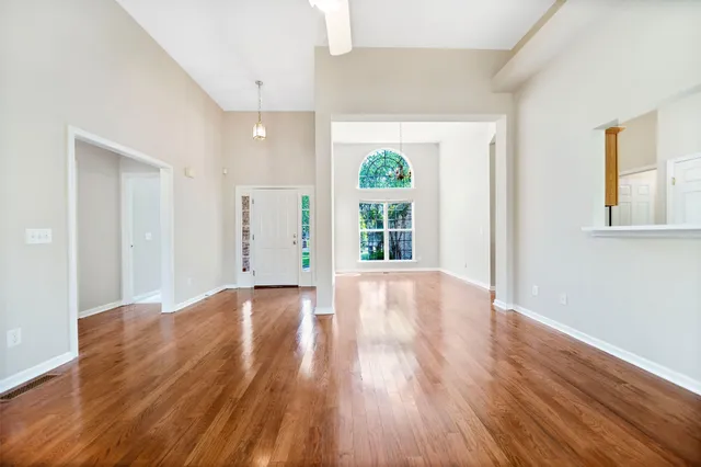 a view of an empty room with wooden floor and a window