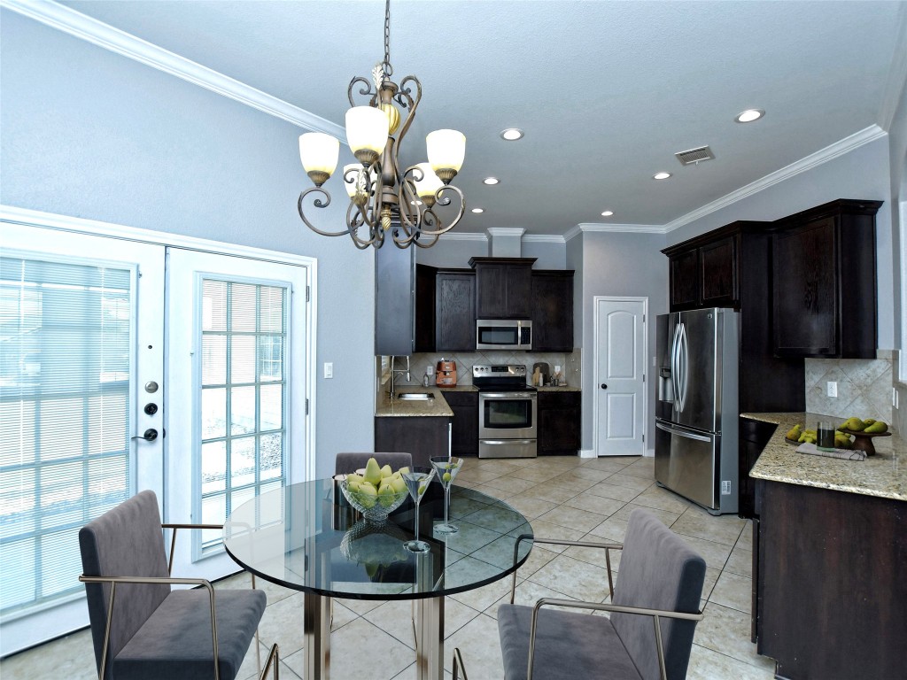 217 Geode Lane Jarrell, TX 76537 - Photo 13 of 35 Dining space featuring crown molding, light tile floors, recessed lighting, and a chandelier