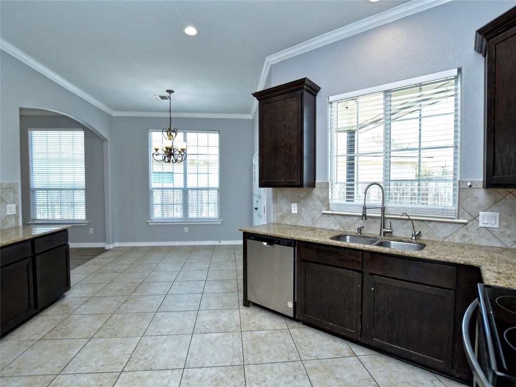 217 Geode Lane Jarrell, TX 76537 - Photo 16 of 35 Kitchen featuring backsplash, dark brown cabinets, crown molding, stainless steel range with electric stovetop, and light granite countertops