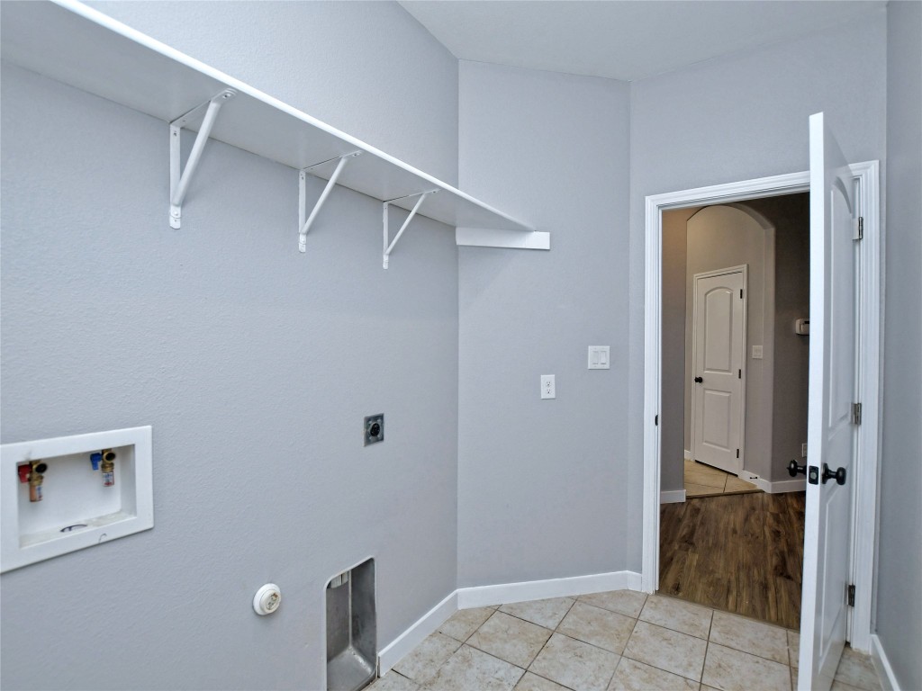 217 Geode Lane Jarrell, TX 76537 - Photo 18 of 35 Laundry room with light tile patterned floors, electric dryer hookup, washer hookup, and with washer and dryer included in sale.