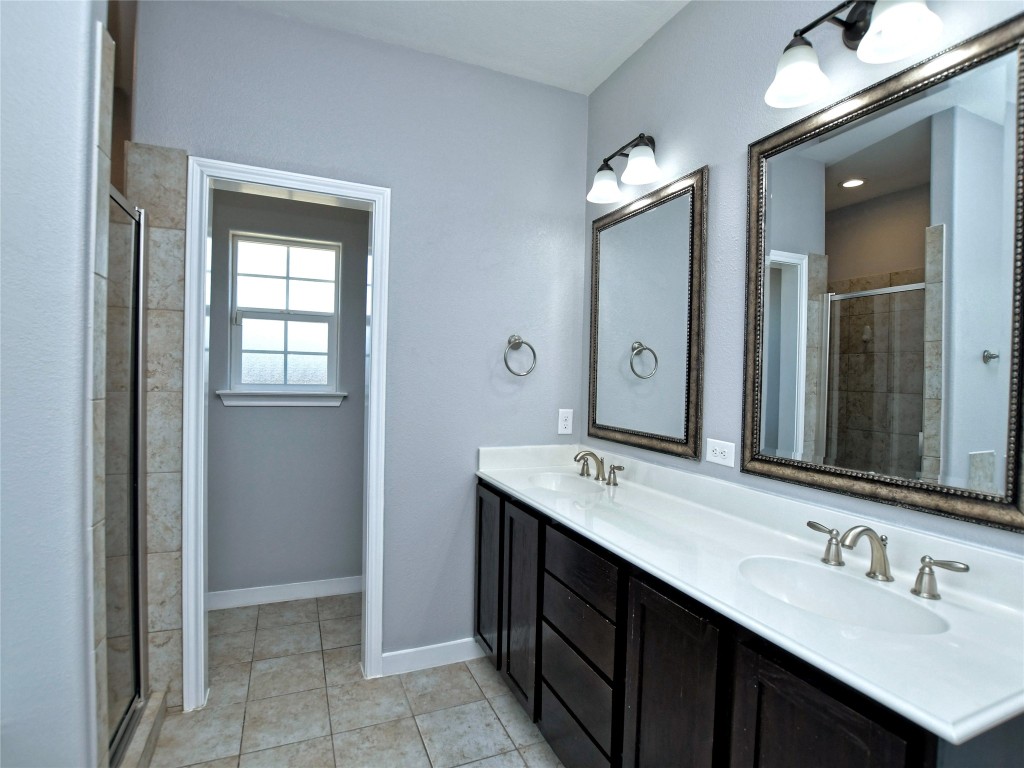 217 Geode Lane Jarrell, TX 76537 - Photo 24 of 35 Bathroom with double vanity, a shower stall, and light tile flooring