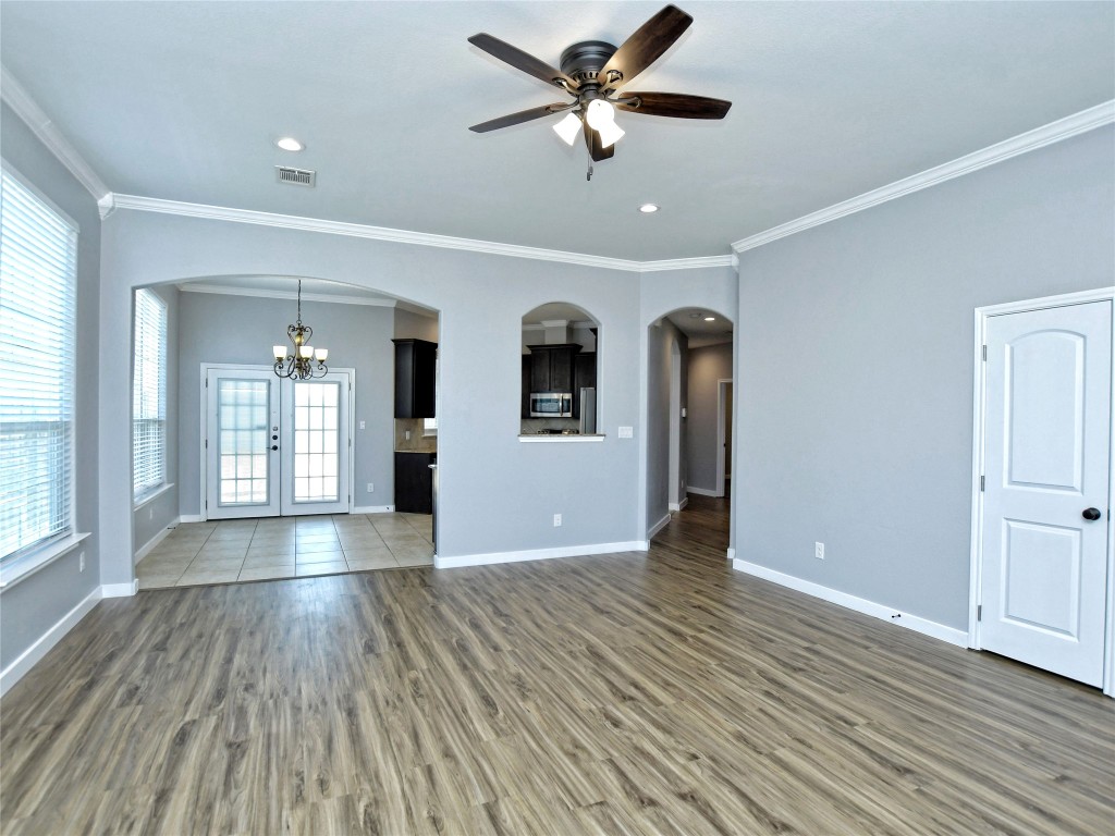 217 Geode Lane Jarrell, TX 76537 - Photo 7 of 35 Unfurnished living room featuring crown molding, arched walkways, a chandelier, light wood-style flooring, and recessed lighting