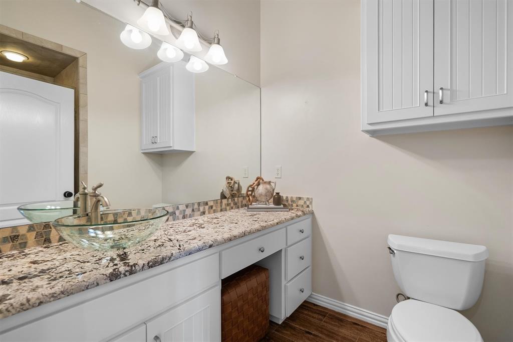 2431 Dr Sanders Road Cross Roads, TX 76227 - Photo 22 of 40 a bathroom with a granite countertop toilet sink and mirror