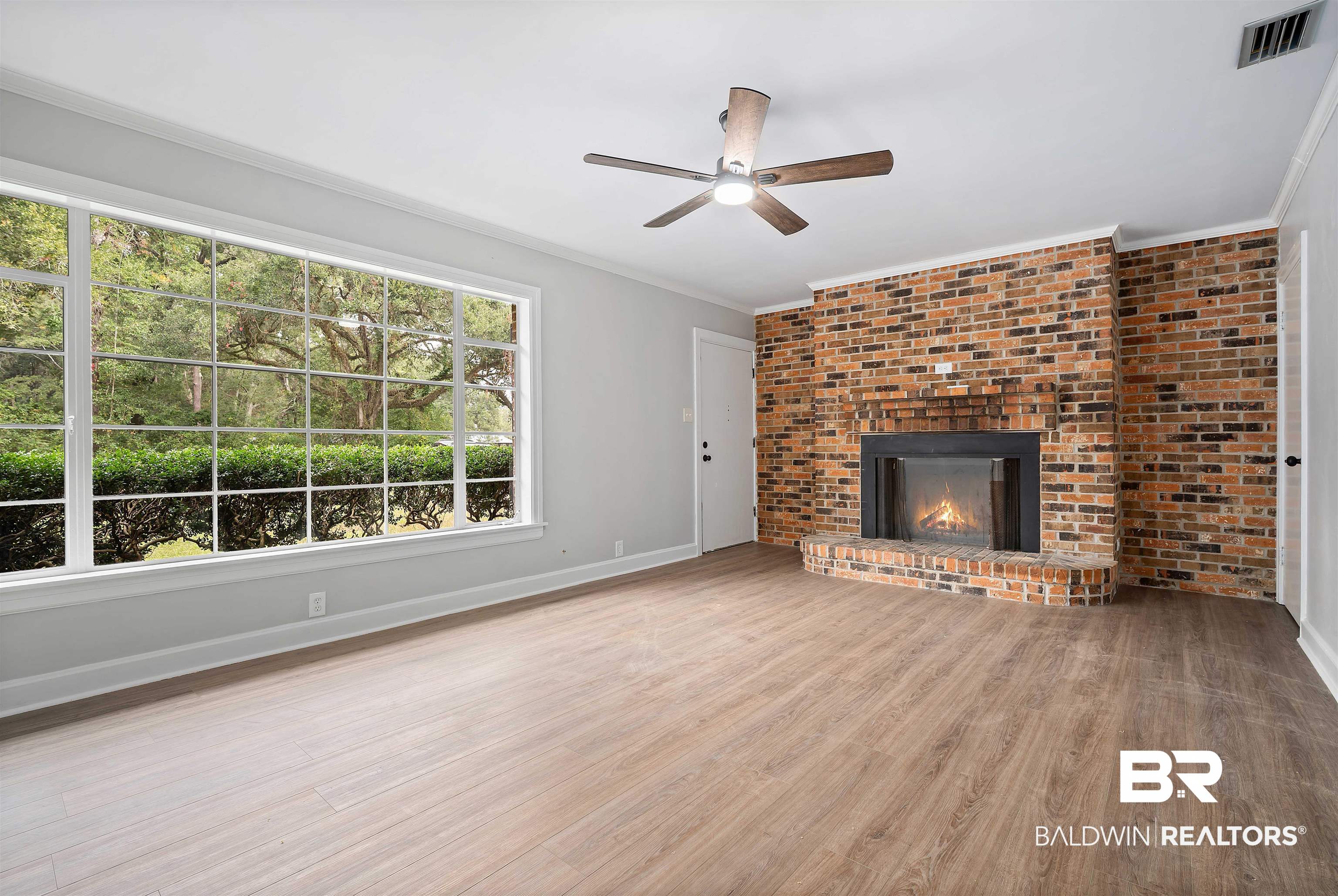 2261 Island Road Mobile, AL 36605 - Photo 7 of 25 Unfurnished living room with light wood-style floors, a fireplace, ceiling fan, and crown molding