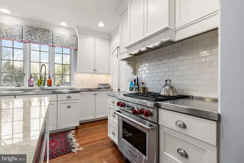 a kitchen with stainless steel appliances a stove a sink and a white wooden cabinets