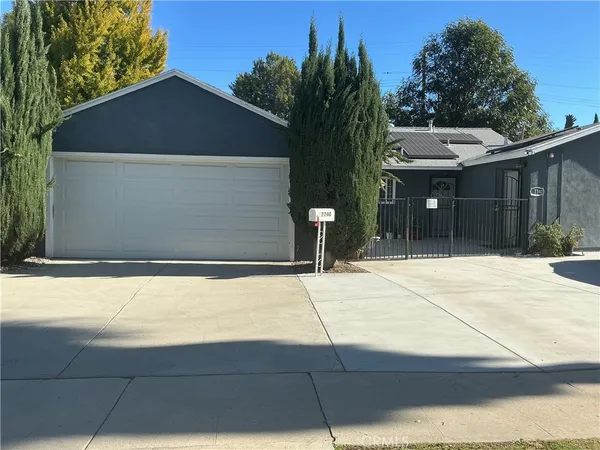 a backyard of a house with large trees and plants