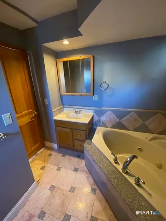 a bathroom with a tub sink and mirror