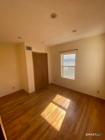 an empty room with wooden floor cabinet and windows