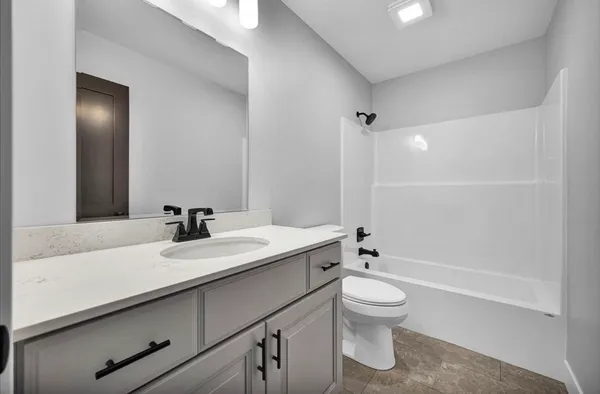 a bathroom with a granite countertop sink a toilet and a large mirror