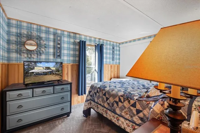 a bedroom with a bed and a flat tv screen on dresser