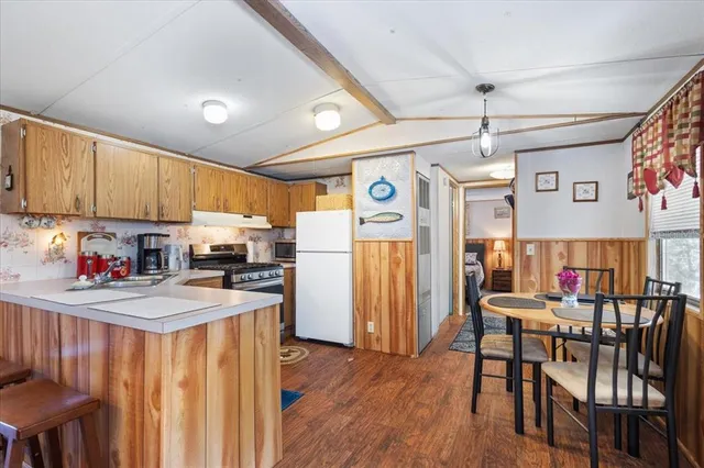 a kitchen with stainless steel appliances kitchen island granite countertop a refrigerator a stove top oven a sink dishwasher and white cabinets with wooden floor
