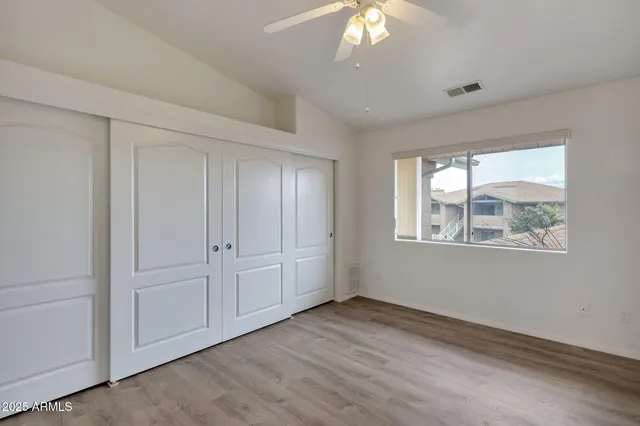 a view of an empty room with a window and chandelier fan