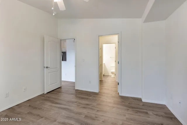 a view of an empty room with wooden floor and closet