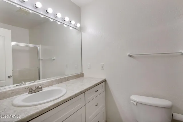 a bathroom with a granite countertop sink a toilet and a mirror