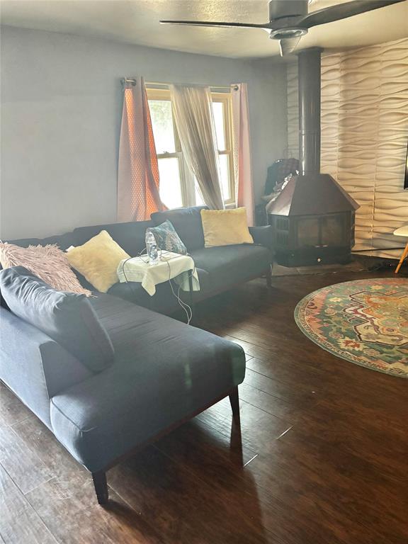 1326 Texas Street Vernon, TX 76384 - Photo 18 of 25 Living room featuring a wood stove, wood-type flooring, and ceiling fan