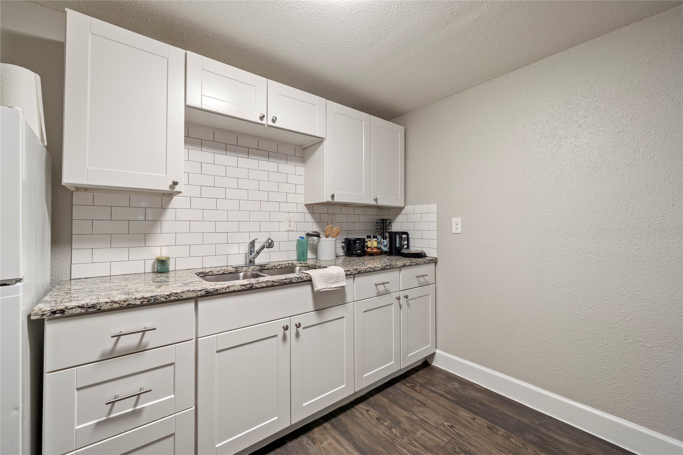 201 West 31st Street, Unit E Austin, TX 78705 - Photo 11 of 16 A compact kitchen with sleek granite counters and white subway tile backsplash for everyday convenience.