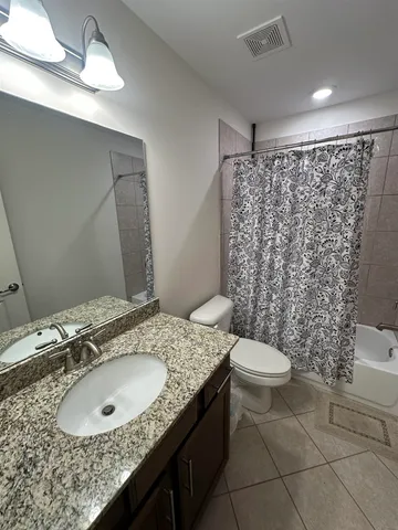 a bathroom with a granite countertop sink toilet and shower