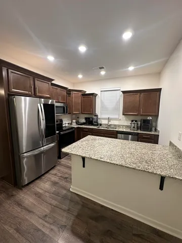 a kitchen with stainless steel appliances granite countertop a refrigerator a sink a stove a microwave and cabinets