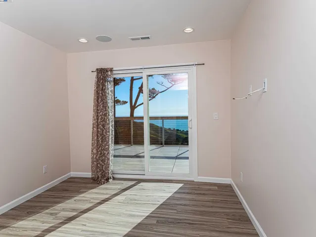a view of a hallway with wooden floor and a bathroom