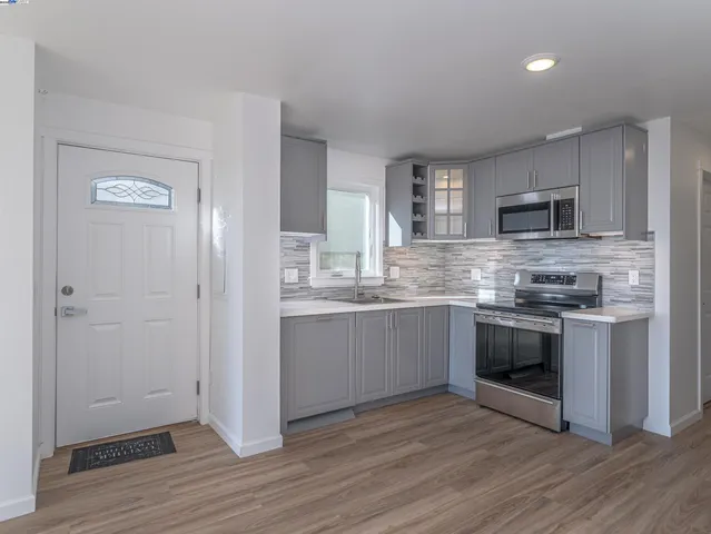a kitchen with granite countertop a refrigerator and a stove top oven