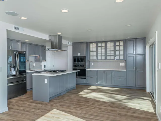 a kitchen with stainless steel appliances kitchen island granite countertop a refrigerator and a stove top oven