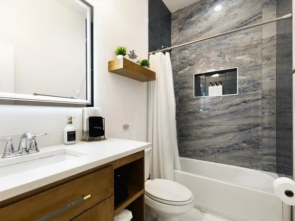 a bathroom with a granite countertop sink a toilet and shower
