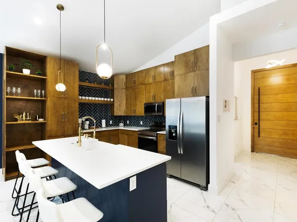 a kitchen with stainless steel appliances kitchen island granite countertop a refrigerator a sink a stove and island