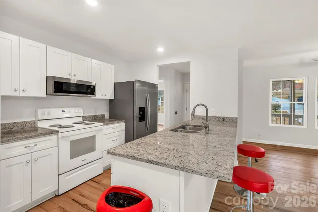 a kitchen with granite countertop a sink a counter top space appliances and cabinets