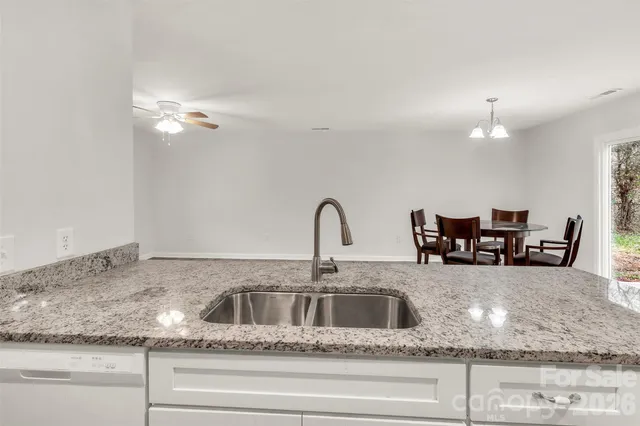 a kitchen with kitchen island granite countertop a sink and refrigerator