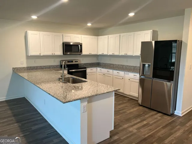 a kitchen with stainless steel appliances granite countertop a sink dishwasher a refrigerator and a stove with wooden floor