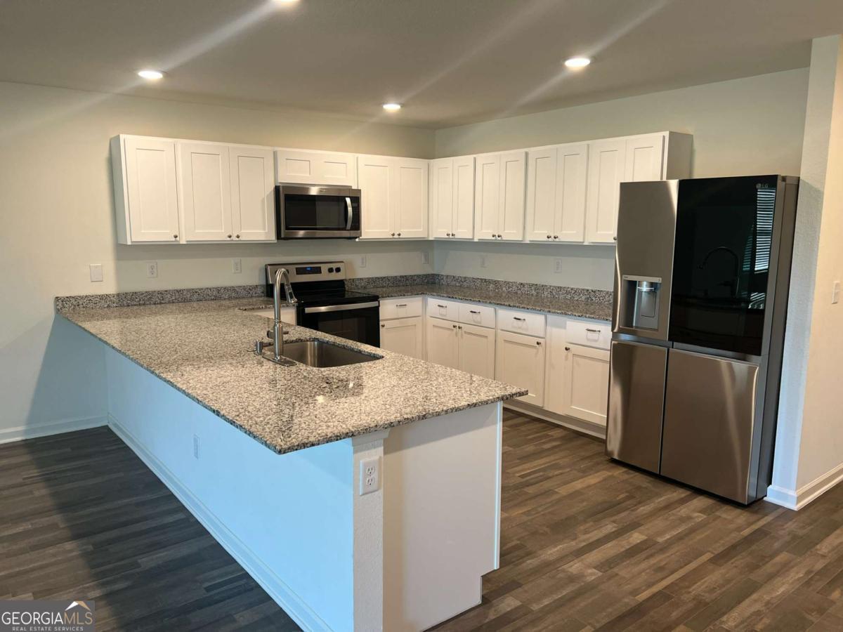 127 Oarsman Crossing St. Marys, GA 31558 - Photo 11 of 17 a kitchen with stainless steel appliances granite countertop a sink dishwasher a refrigerator and a stove with wooden floor