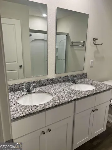 a bathroom with a granite countertop sink and a mirror