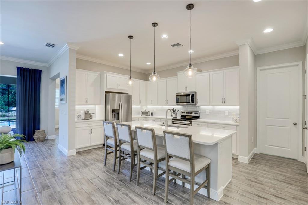 3528 Pilot Circle Naples, FL 34120 - Photo 14 of 46 a kitchen with stainless steel appliances a dining table chairs stove and refrigerator