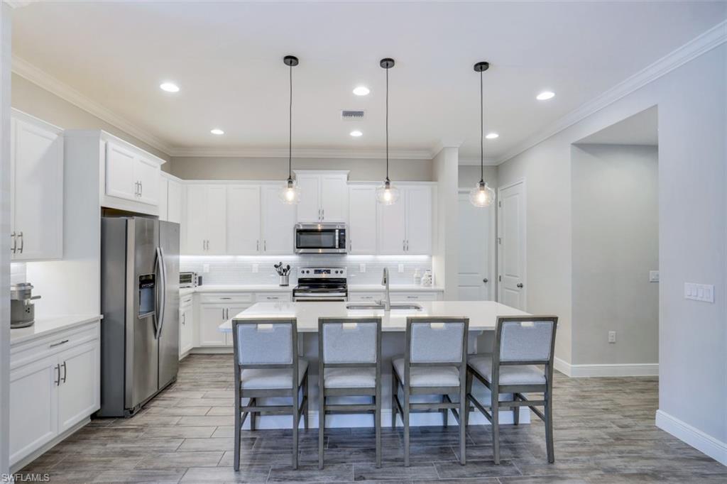 3528 Pilot Circle Naples, FL 34120 - Photo 18 of 46 a kitchen with stainless steel appliances a dining table chairs refrigerator and sink