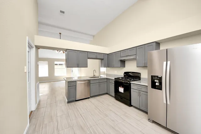 a kitchen with a refrigerator a stove top oven a sink and dishwasher with wooden floor