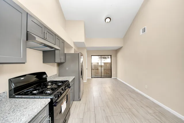 a kitchen with stainless steel appliances granite countertop a stove and a wooden floor