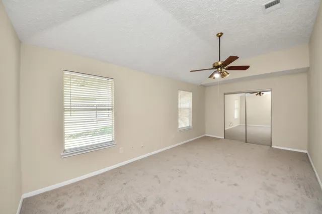a view of an empty room with window and chandelier fan