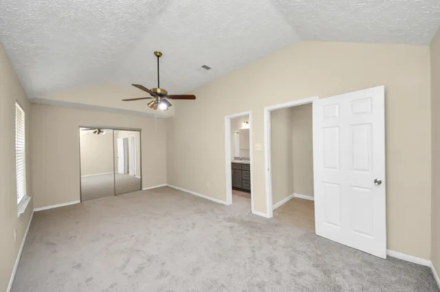 an empty room with chandelier fan and closet area
