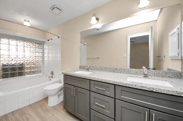 a bathroom with a granite countertop sink mirror vanity bathtub and toilet