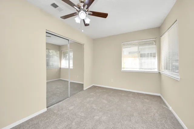 an empty room with windows and fan