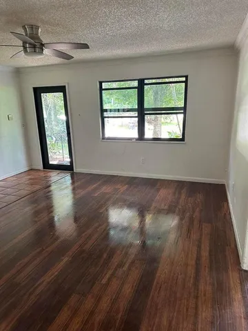a view of an empty room with wooden floor and a window
