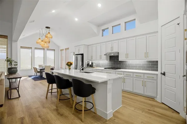 a kitchen with stainless steel appliances a white table chairs and a refrigerator