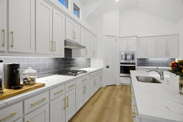 a kitchen with kitchen island granite countertop a sink a stove and cabinets