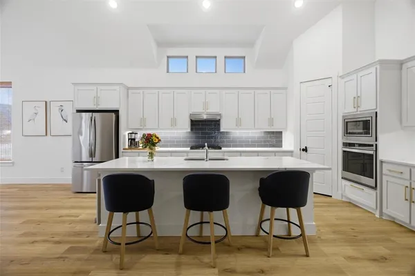 a kitchen with stainless steel appliances granite countertop a stove a refrigerator a sink a dining table and chairs with wooden floor