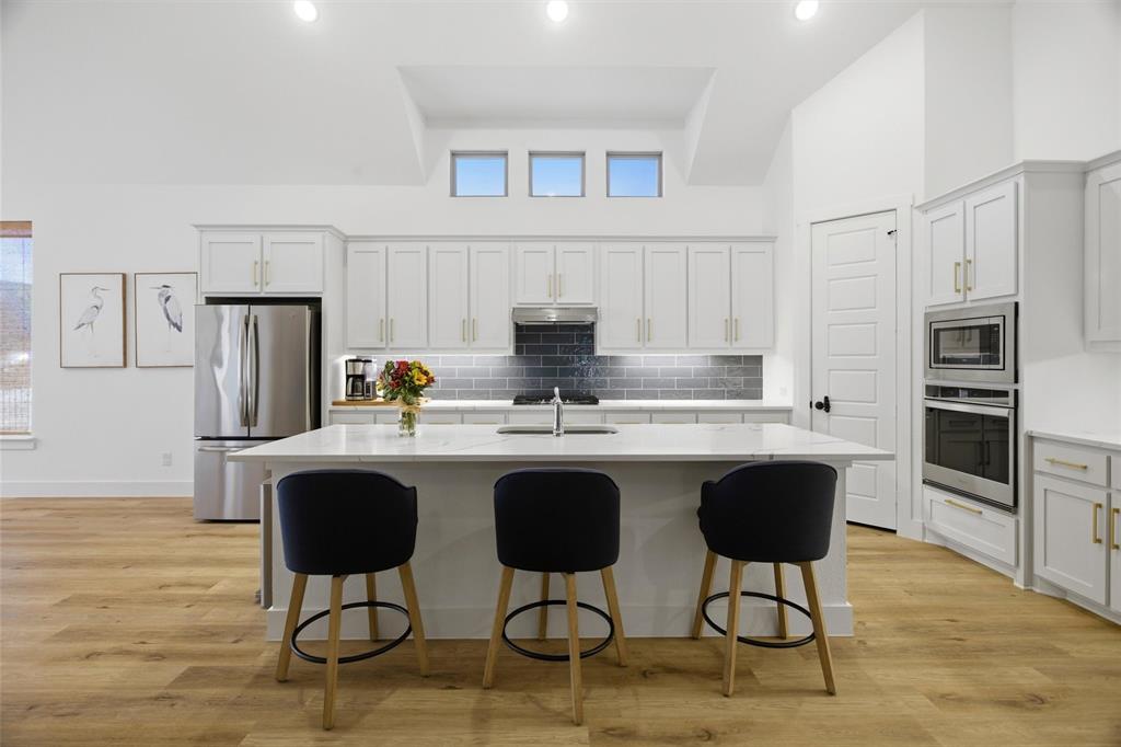 6033 Strada Cove Fort Worth, TX 76123 - Photo 10 of 35 a kitchen with stainless steel appliances granite countertop a stove a refrigerator a sink a dining table and chairs with wooden floor